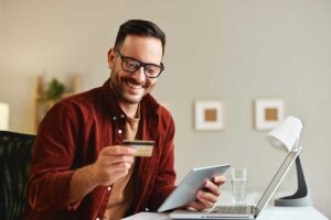 A local family reviews their finances together at the dining table, looking at papers, a laptop, and a calculator.
