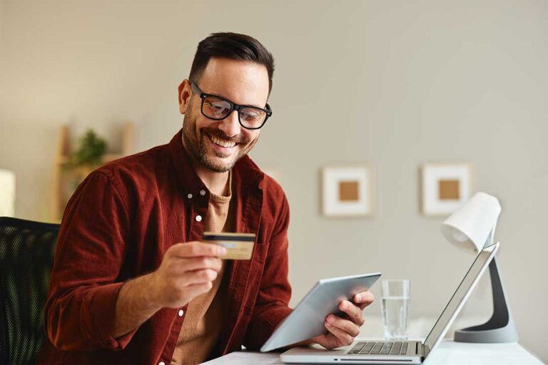 A local family reviews their finances together at the dining table, looking at papers, a laptop, and a calculator.